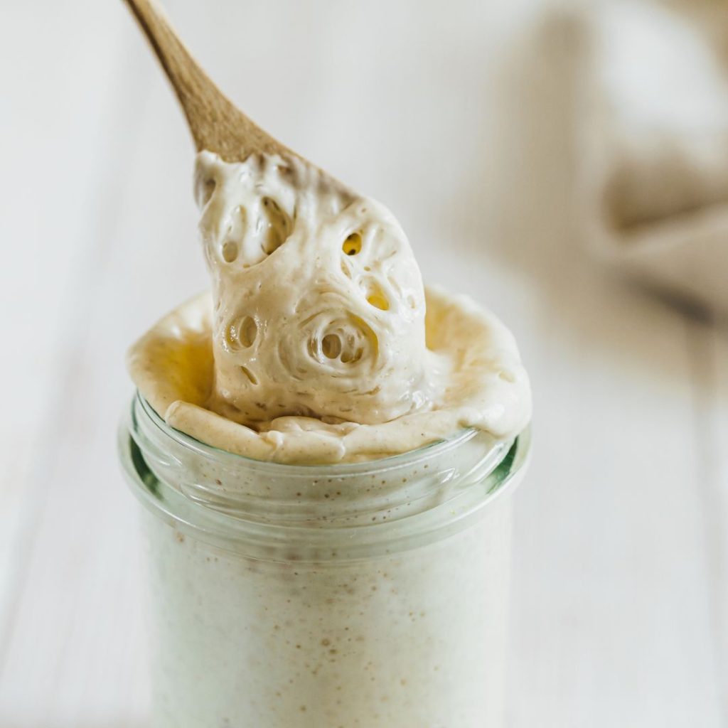 Jar of sourdough culture with wooden spoon